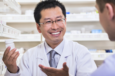 smiling pharmacist showing prescription medication to a customer